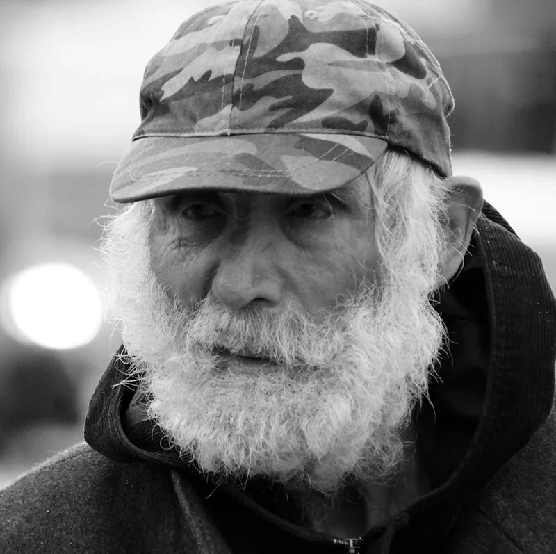 Black and white photo of older veteran man where camo hat